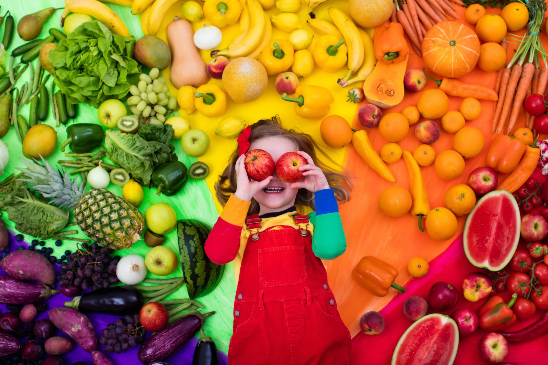 Dziewczynka w otoczeniu warzyw i owoców
