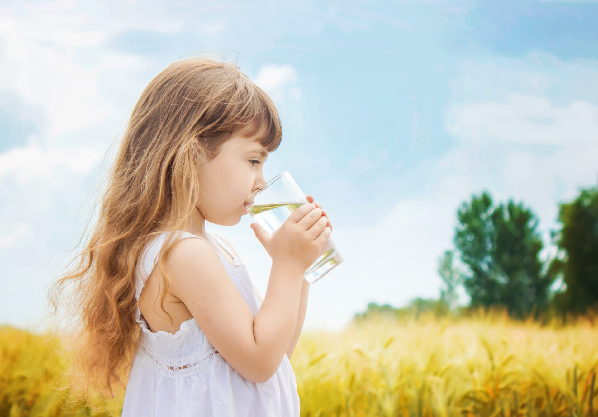 Dziewczynka ze szklanką wody, w tle polana
