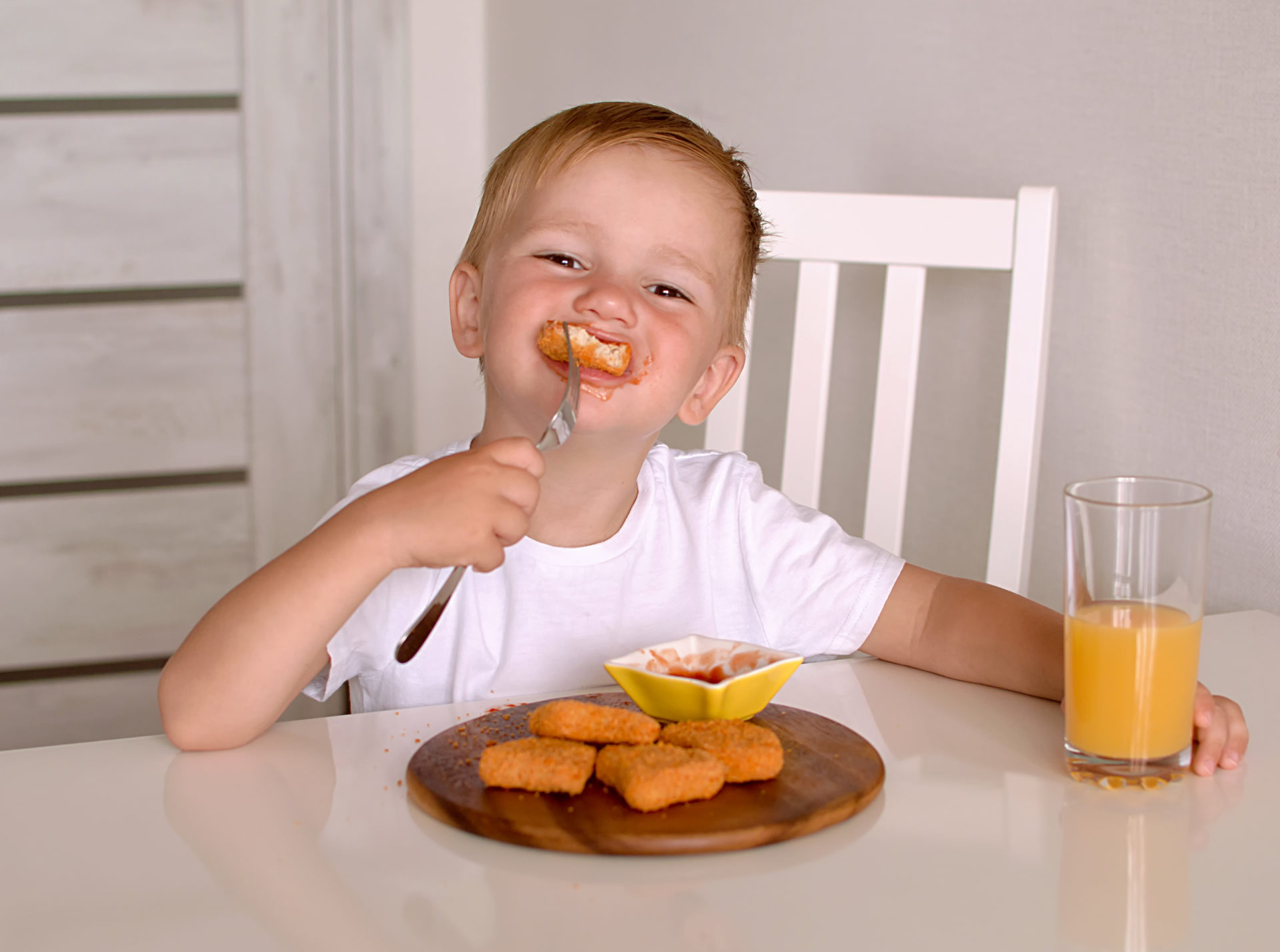 Chłopiec zjada domowy obiad - nuggetsy z kurczaka